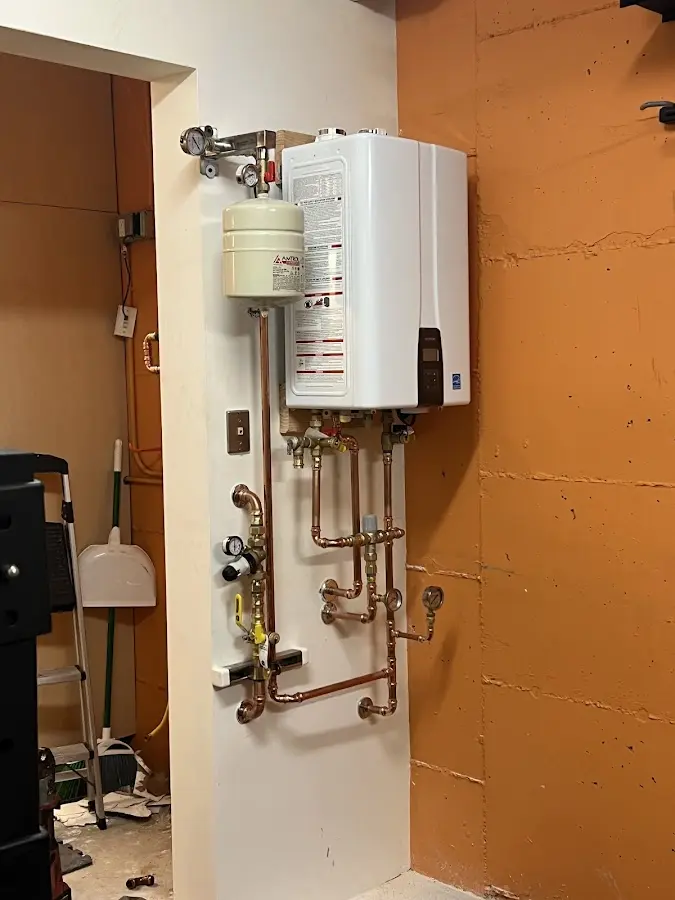 Plumbing technician inspecting water heater connections in Thompson